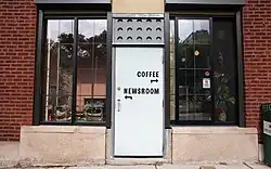 An office's entrance door with signs that direct visitors to "coffee" and "newsroom"