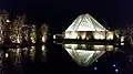 The prayer hall illuminated at night, reflected in one of the ponds of the formal garden