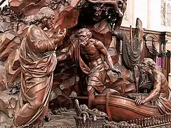 depiction of a life size wooden carving of Jesus calling Peter and Andrew as they climb out of their fishing boat