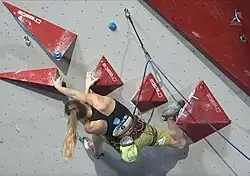 A climber using the drop-knee technique on an indoor climbing wall