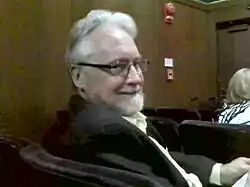 Photograph of a white man in his late 60s with glasses and a beard.
