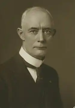 1909 black and white head and shoulders photo of John H. Fraine in suit and tie, facing to his left, looking towards camera