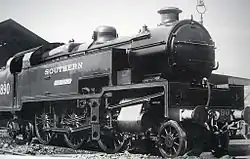 Side-and-front view of the 3-cylinder version of the locomotive. The distinguishing feature is a full-width flat panel rising vertically above the front buffer beam to the level of the bottom of the smokebox door. The water tanks are a different shape from the K&nbsp;Class, as they include a rectangular access hole in the side, bottom-front, for maintaining the valve gear, which is also different from the K&nbsp;class.