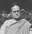 A middle-aged white woman with hair braided across her crown. She is wearing eyeglasses and a sari.