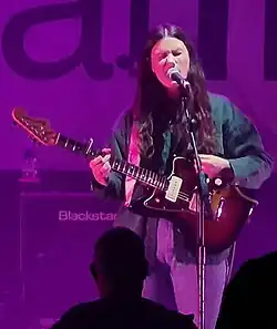 Malco singing into microphone while playing guitar