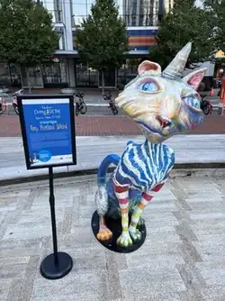 Photograph of a colorful statue of a cat and an explanatory sign