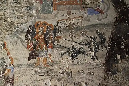 Heavily damaged fresco on stone with text in Greek.