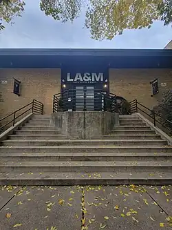 Double-doored entrance to a one-story brick building with stairs leading up to the doorway.