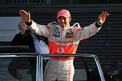 Lewis Hamilton with his arms raised in his McLaren racesuit and cap at 2008 Stars & Cars