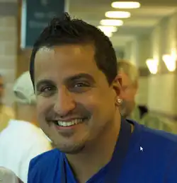 Portrait of Lucas Prata smiling at the camera while wearing a blue shirt.