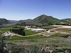 An overview photo of buildings and fields at the Lucky Peak Nursery from a hillside above it
