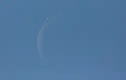 venus next to a crescent moon in the blue daytime sky