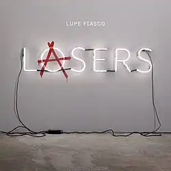 Image of a gallery setting, where a LOSERS sign is plugged into the wall. Superimposed over the 'O' is the red anarchist 'A' to read LASERS.