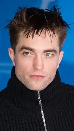 Pattinson, wearing a black jumper, looking to his right