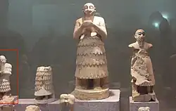 Statues from Mari. The statue of Ishqi-Mari appears partially on the left: it is much smaller than many of the traditional Mari statues.[1] Aleppo National Museum.