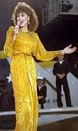 Marie Osmond, wearing a yellow dress and singing into a microphone.