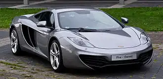 Silver sports car with prominent silver five-spoke wheels and a licence plate that says "Pre-Owned"