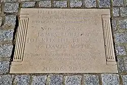 A memorial plaque reading "United Forever / Never will we walk by without remembering you / In memory of James Furlong / Joe Richie-Bennett / & David Wails / To James, Joe and David, their families and all of those affected/ 20.06.2020"