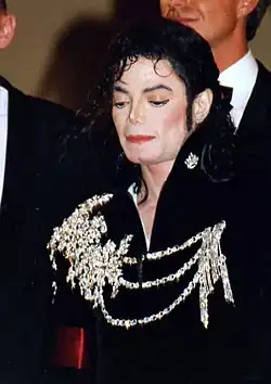 Close-up of a pale skinned Jackson with black hair. He is wearing a black jacket with white designs on it.