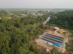 Photograph of a solar mini-grid in a green forest serving a rural village taken from a drone