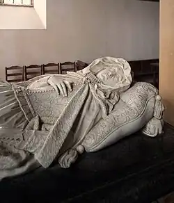 This image shows the remarkable marble effigy of Lady Carey at Stowe-Nine-Churches, Northamptonshire, created by Nicholas Stone in 1620. The sculpture demonstrates Stone's revolutionary approach to monument design, depicting Lady Carey in a naturalistic and relaxed pose rather than the rigid formality typical of earlier periods. She is shown as an elderly woman reclining on her side on an ornate cushion, her head turned slightly and resting on her hand in a contemplative attitude. The effigy displays exceptional attention to detail in the carving of her flowing robes, lace collar, and the decorative scrollwork of the cushion beneath her. Notably, this monument was commissioned during Lady Carey's lifetime, allowing Stone to create a genuine portrait rather than a generic representation. The work exemplifies the shift towards more personalised and emotionally engaging monument sculpture that characterised the early seventeenth century, moving away from medieval conventions towards a more humanised approach that would influence English funerary art for generations to come.