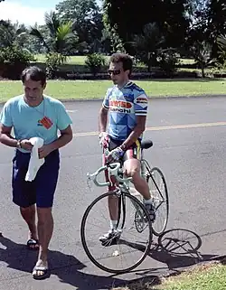 A man on straddling a bike in sunglasses.