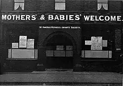 Building with the words "The Mothers' and Babies' Welcome" in large white capital letters, above the door and windows
