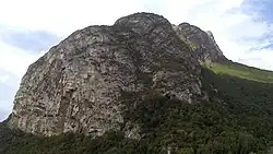 Ridge of a mountain seen in low angle with a cave at its base.