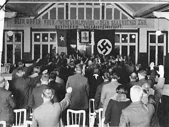 Black-and-white photograph of people performing a Nazi salute, returned by Nazis up front
