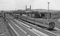 A black and white image of an electric multiple unit on the furthest of four tracks.