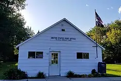 Small white wooden building. The sign reads "United States Post Office, Nielsville, Minnesota 56568".