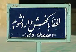 Sign in Persian and English, instructing people to remove their shoes
