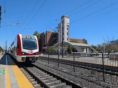 A Caltrain EMU arriving across the ticketing area and parking garage