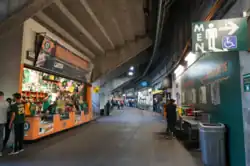A shot of the concourse showing a vendor of A's merchandise, a bathroom sign, and entrances to the stadium seating