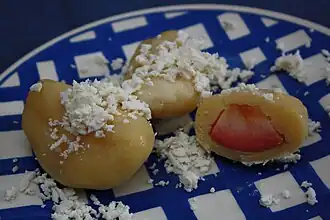 dumplings on a plate, one cut open to show fruit inside, all topped with cottage cheese