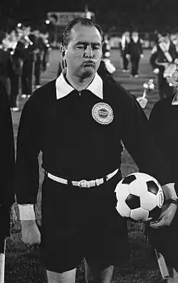 Black and white photo of a man in black with a white football.