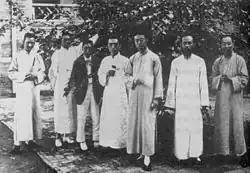 A black and white photo of a group of men outside on a patio. Gu Jiegang and Hu Shih are in the center.