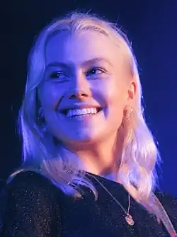 A young Caucasian woman looking sideways with blue and purple lights covering her face