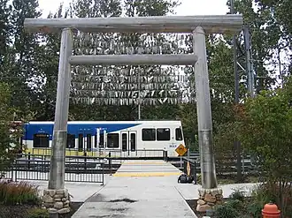 Timber gateway and a waiting train. Facsimiles of historical newspaper headlines are at the base of the wooden poles.