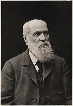 Head and shoulders of bald-headed, heavily bearded man looking to right