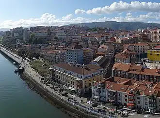 View of the coast of Portugalete which includes a concrete wall separating the water (below) from several apartment buildings (above) with a street between them