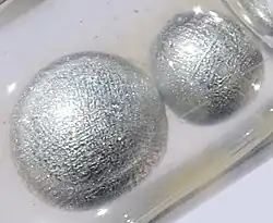 Two spherical beads of potassium metal in a container filled with oil