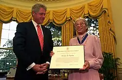Bill Clinton standing next to an elderly Rosa Parks, who is holding a certificate indicating that she has been awarded the Presidential Medal of Freedom