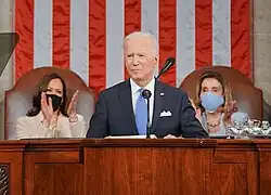 Photo of Biden giving a speech to Congress, with Pelosi and Harris clapping behind him