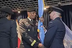 General Brooks, as commander of the UN Command, pictured assigning command of UN Command–Rear by handing the UN flag to Royal Australian Air Force Group Captain Adam Williams in 2018