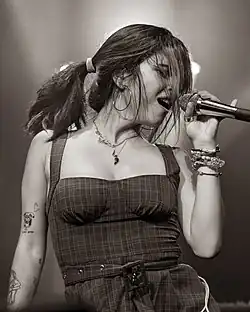 A woman is singing on stage while holding a microphone in her hand.