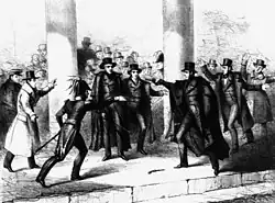 Several people in a crowd, man aims a gun at Jackson