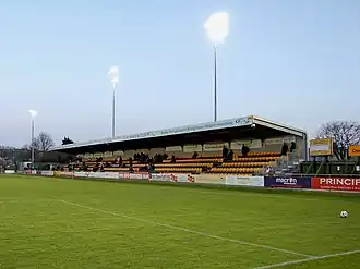 A grandstand at a sports venue. The seats are black and gold.