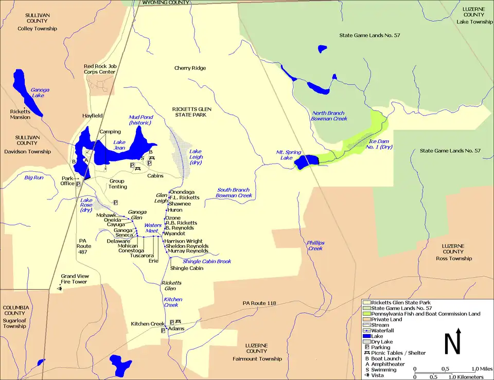 A map showing Kitchen Creek flowing southeast from Ganoga Lake, through Lake Jean, and then through the dry bed of Lake Rose into Ganoga Glen with ten waterfalls. A second branch of the creek flows south through the dry bed of Lake Leigh, then through Glen Leigh and its eight waterfalls. These branches meet at Waters Meet and the creek flows south through Ricketts Glen and its six waterfalls. The South Branch Bowman Creek is east of Lake Leigh and Big Run is west of Lake Rose. Pennsylvania Route 487 runs north-south at left, and Pennsylvania Route 118 runs east-west at the bottom of the map. County borders are also shown.