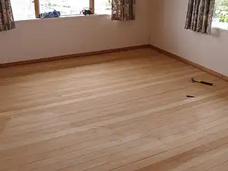 An interior view of an empty room with smooth timber flooring, which is made from D. cupressinum timber.